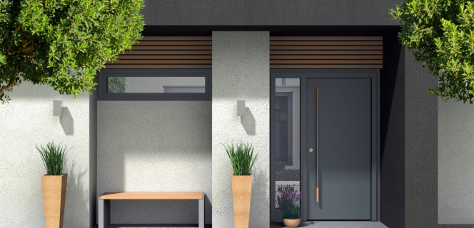 Ein modernes Haus und sein Eingang mit Pflanzen und einer grauen Haustür.