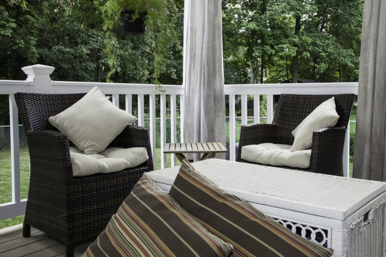 Eine Veranda mit zwei braunen Stühlen und einem Kasten, der auch als Tisch dient.