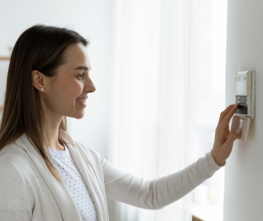 Eine Frau steuert über einen Sender an der Wand eine moderne Lüftungsanlage in ihrem Haus.