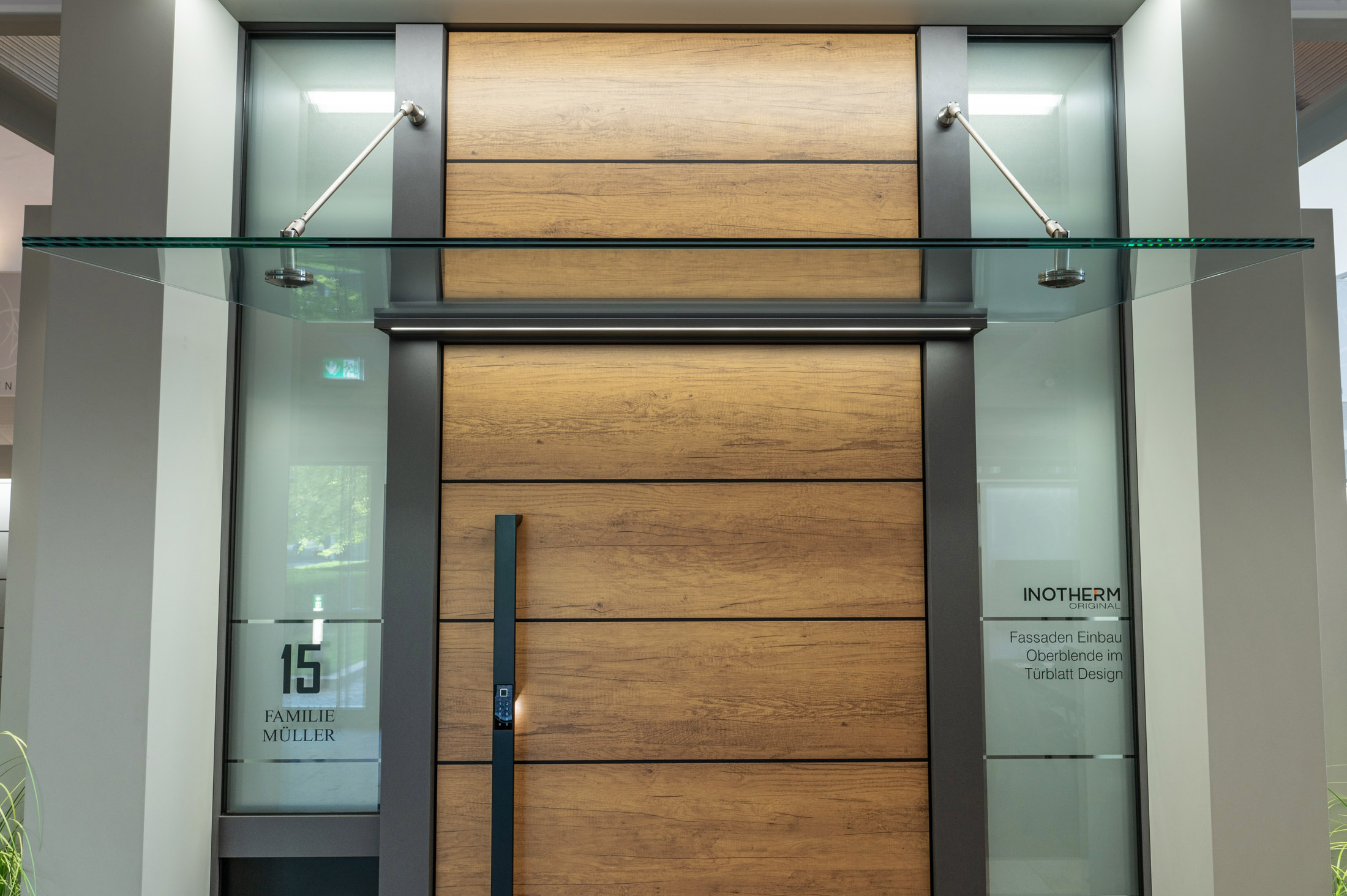 Moderner Hauseingang mit einer schwarzen Tür mit Glaspaneelen, umgeben von einer minimalistischen Fassade und warmer Beleuchtung.